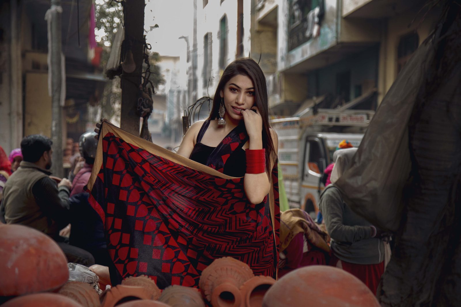 woman standing holding red and black textile near people and vehicles