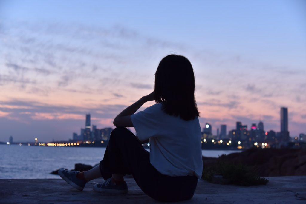 woman in white shirt sitting on the ground during sunset