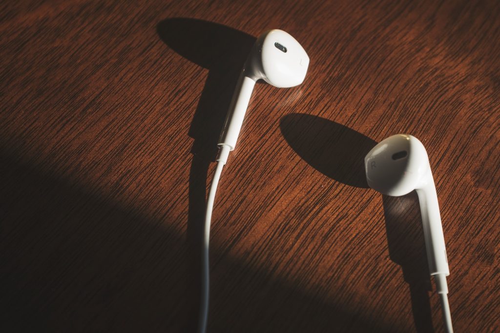 white earbuds on brown wooden table